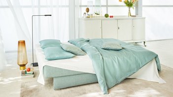 JOKA Perla Doppelliege in Mintgrün, zu einem Bett mit Bettwäsche und Kissen ausgeklappt.