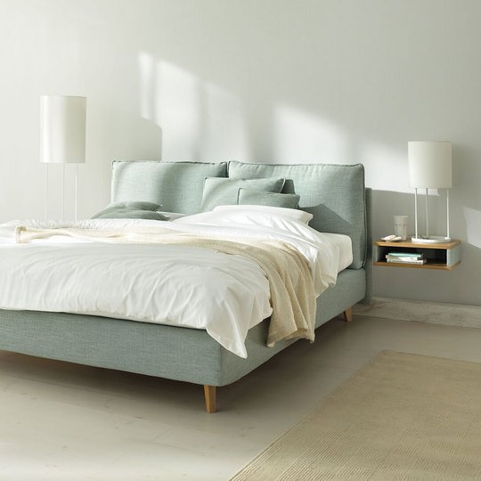 JOKA Arte Boxspringbett in Hellgrün mit weißer Bettwäsche und Holzfüßen im hellen Schlafzimmer