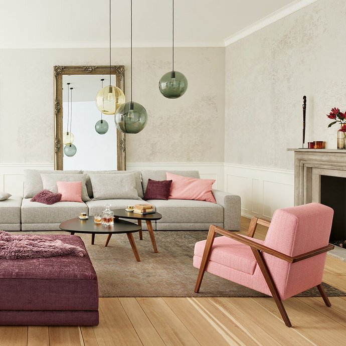Joka Laguna großzügige graue Wohnlandschaft mit rosa Sessel, dunkelviolettem Hocker und Kamin