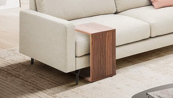 Helles, modernes Wohnzimmer mit einem hellen 3-Sitzer-Sofa, an das ein passender Holz-Beistelltisch geschoben ist.