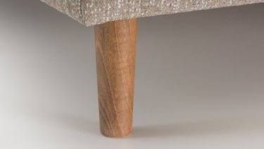 Detailansicht eines runden, nach unten verjüngten Holzfußes (Kegelfuß) aus hellem Holz.