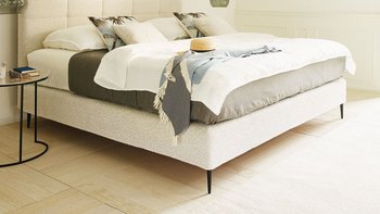 JOKA Mattina Boxspringbett in Hellbeige mit gepolstertem Kassetten-Kopfteil im sonnigen Schlafzimmer mit Poolblick