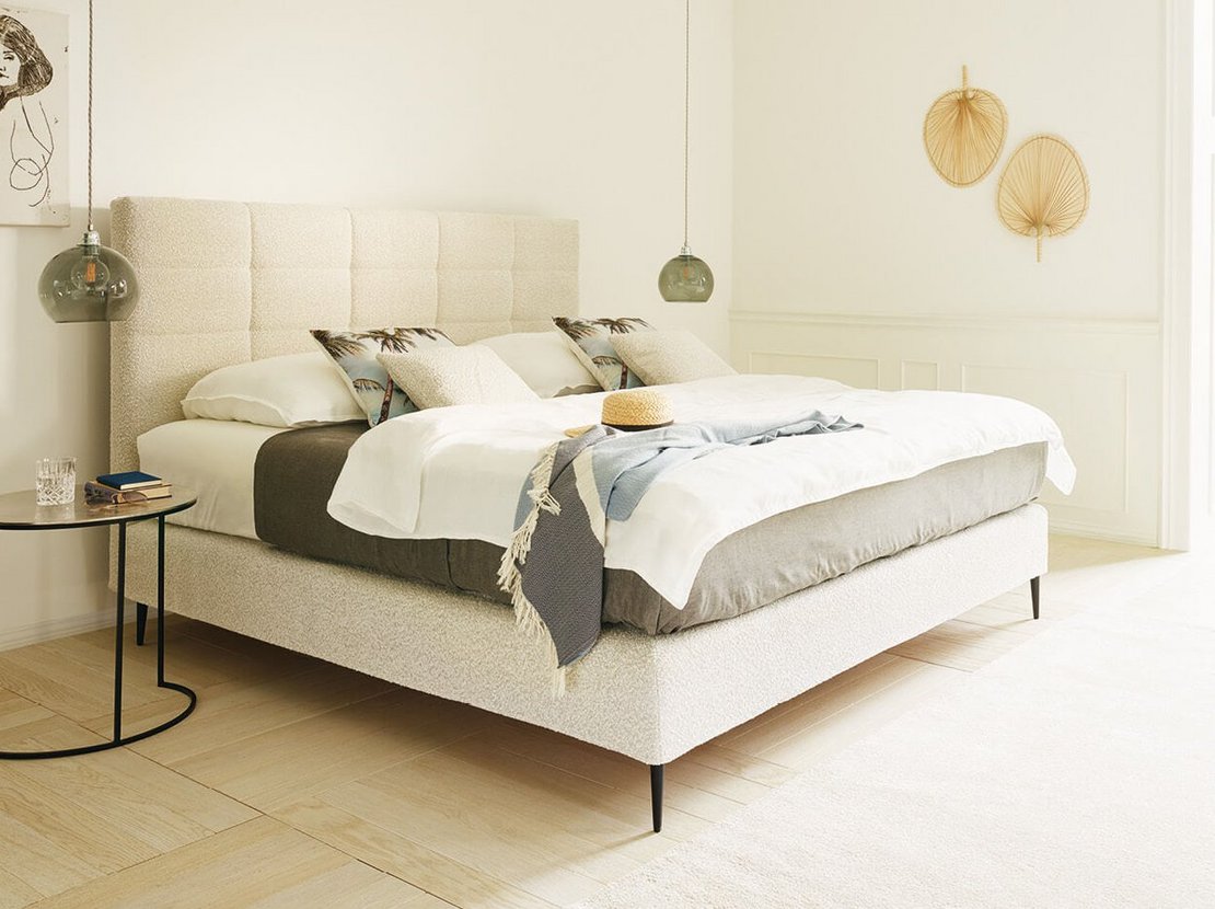 JOKA Mattina Boxspringbett in Hellbeige mit gepolstertem Kassetten-Kopfteil im sonnigen Schlafzimmer mit Poolblick