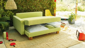 JOKA Quadro Schlafsofa in Hellgrün mit leicht geöffneter Sitzfläche und integriertem Stauraum.