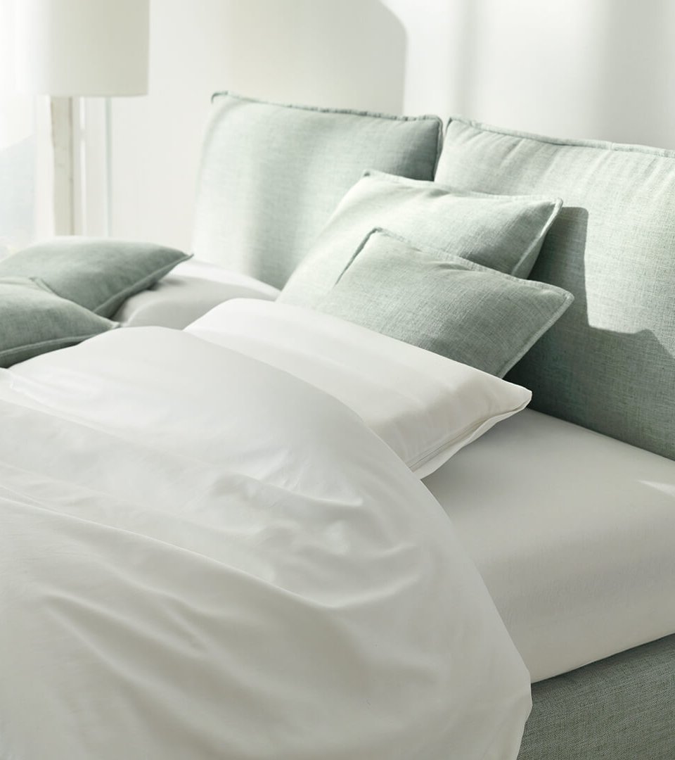 Helles Polsterbett mit lindgrünem Stoffbezug und weißen Kissen im modernen Schlafzimmer
