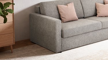 Nahaufnahme der linken Armlehne des JOKA Marea Schlafsofas in Grau, mit Blick auf die Struktur des Stoffes und die angrenzenden Zierkissen.