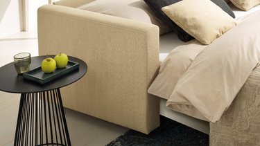Detailansicht der Armlehne des JOKA Magic Längsschläfers in beige, während das Sofa als Bett umgebaut ist.