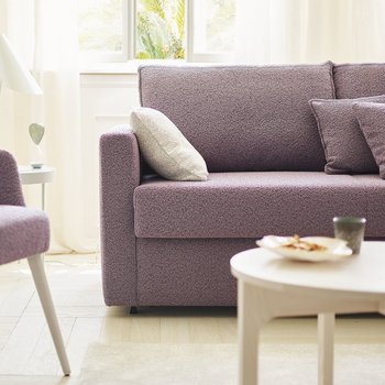 OKA Onda Doppelliege in Lila im Wohnzimmer mit passendem Sessel und Pflanzen.