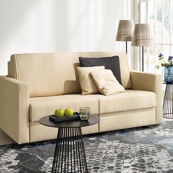joka-magic-laengsschlaefer.jpg: Beige JOKA Magic Längsschläfer Couch dekoriert mit dunklen und hellen Zierkissen in einem hellen Wohnraum mit gemustertem Teppich und schwarzen Beistelltischen.